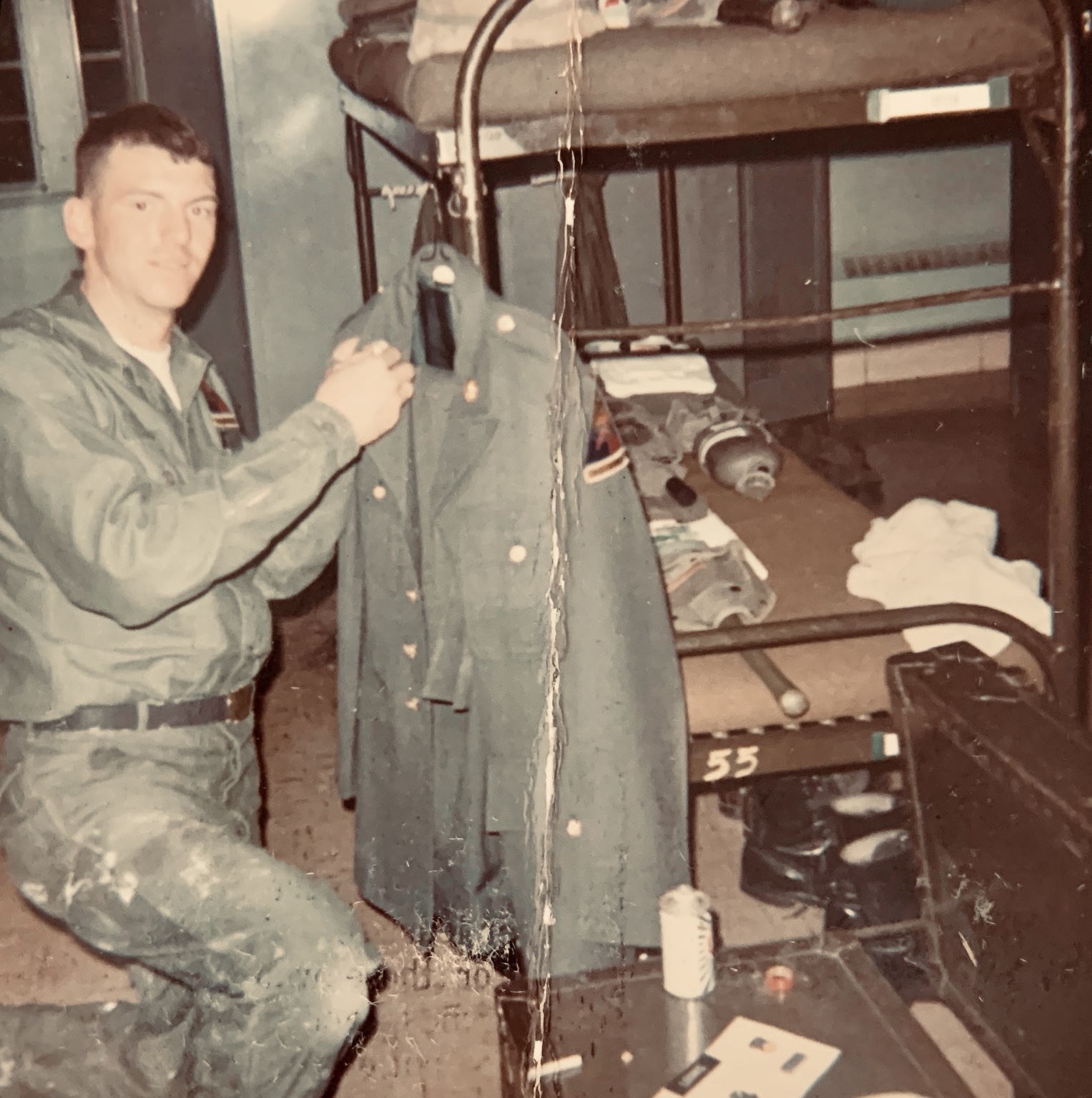 Al Loomis holding his dress uniform beside his barracks bunk during basic training at Fort Hood, Texas. Possibly 1967; year unconfirmed.
