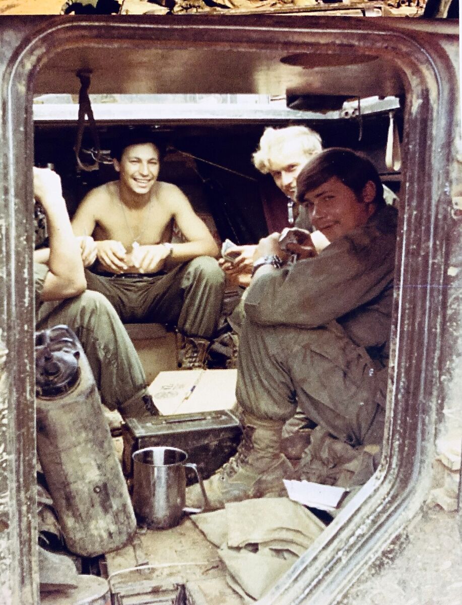 Several troopers seated together inside the open rear of a track