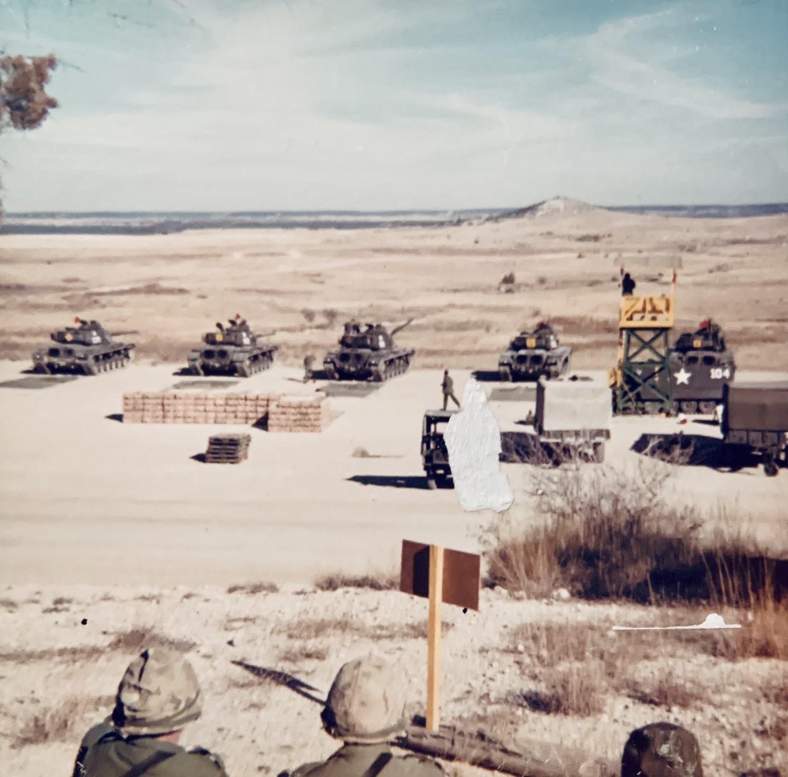 Tanks lined up at a Fort Hood firing range while soldiers observe from the foreground