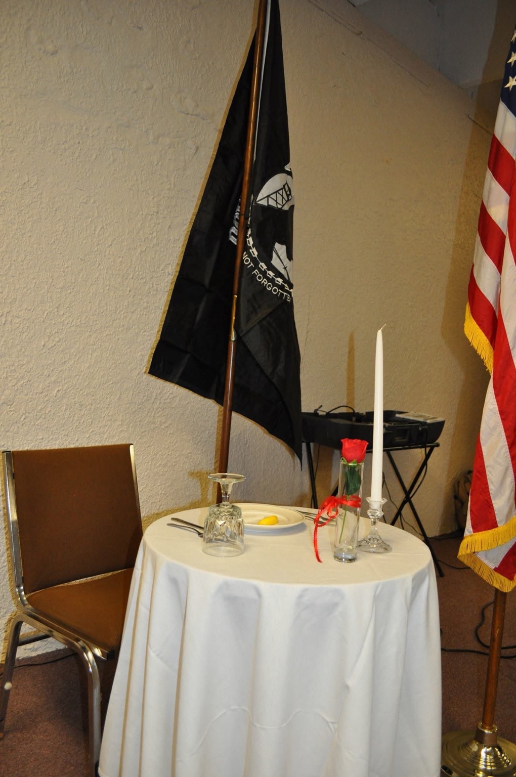 Missing Man Table at an H Troop reunion with an empty chair, inverted glass, lemon, red rose, candle, and POW MIA flag