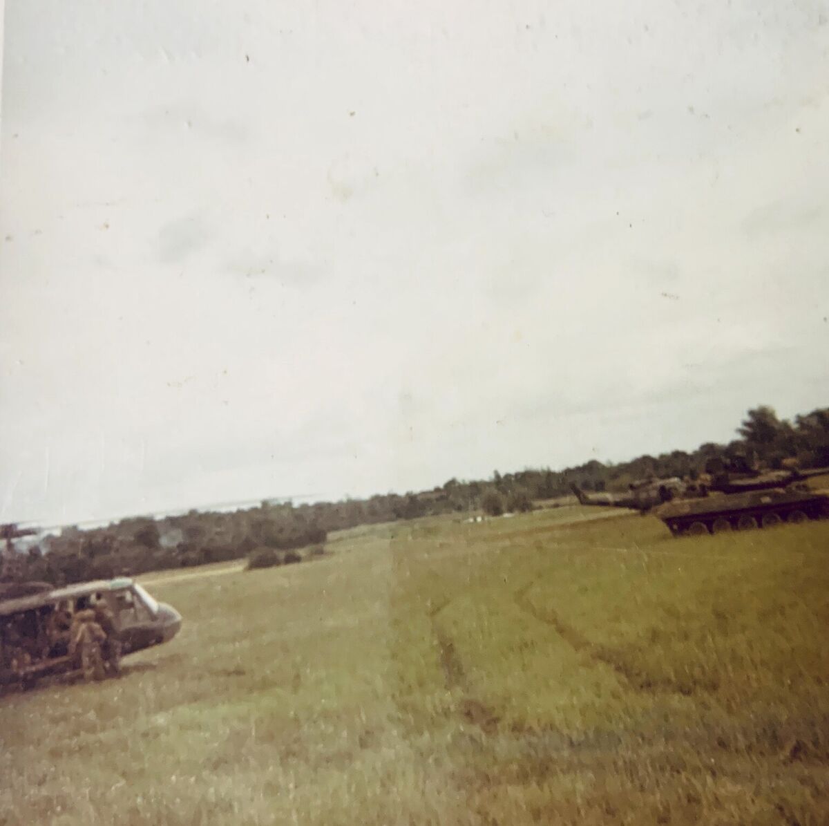 Armored vehicles moving across open green terrain