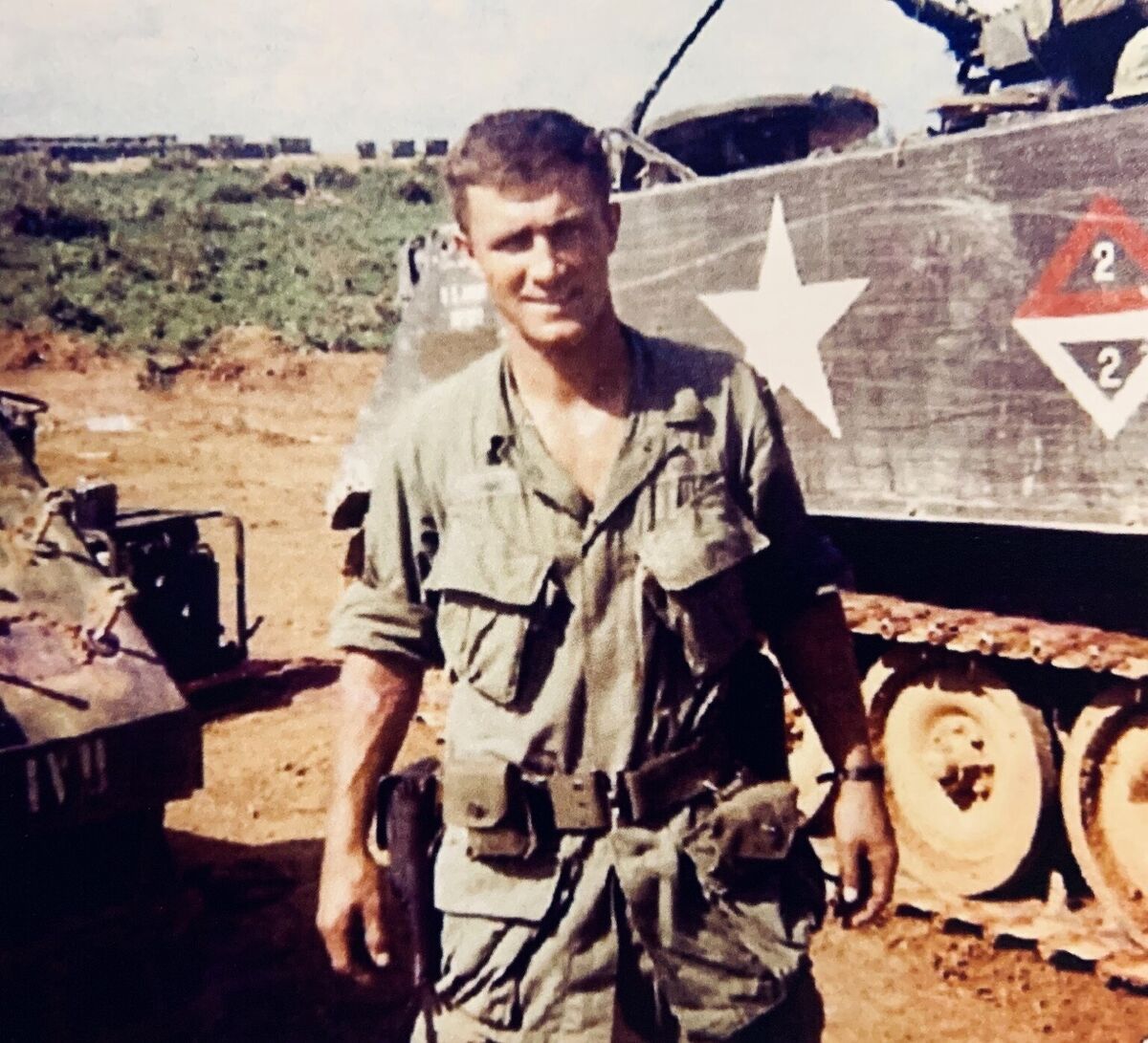 An unidentified H Trooper standing beside an armored vehicle marked 2/2