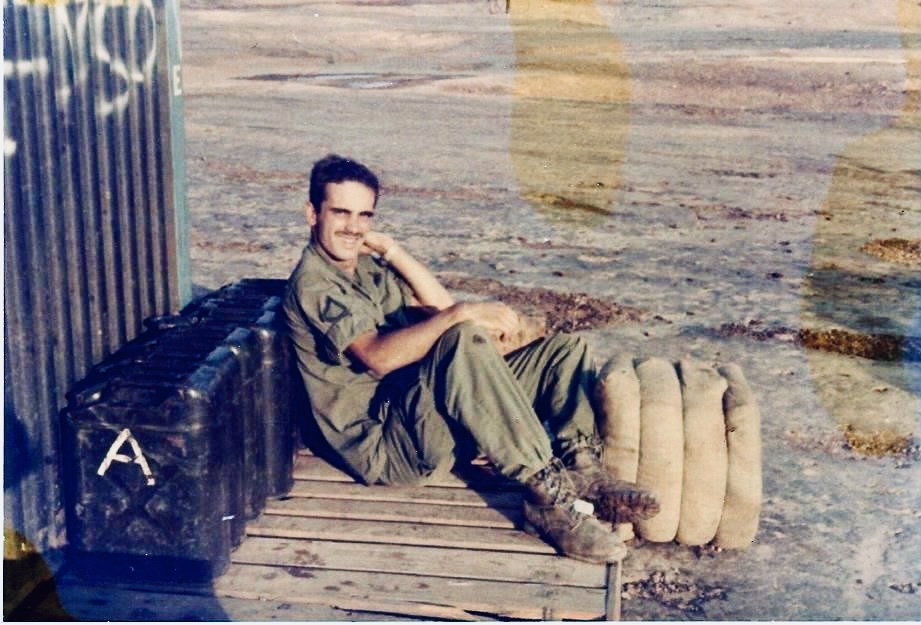 A trooper seated on a wooden platform beside fuel cans and sandbags. Name, date, and location remain unidentified.